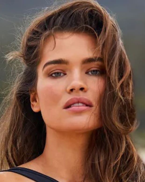 Tara Lynn poses in a black swimsuit and wears her brown hair down.